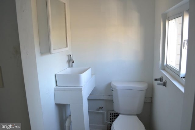 bathroom featuring toilet, sink, and a wealth of natural light