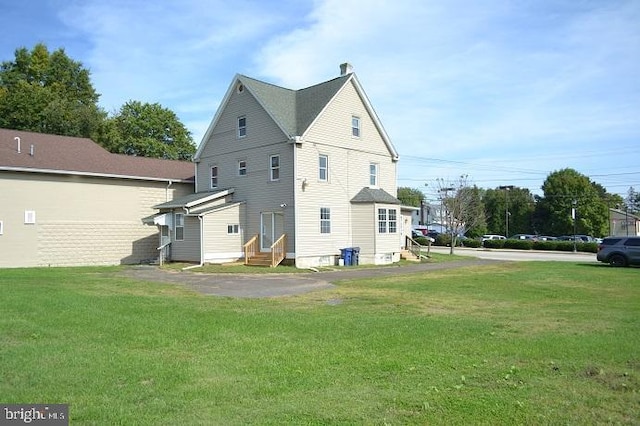 rear view of property featuring a lawn