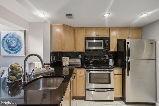 kitchen with appliances with stainless steel finishes, tasteful backsplash, light tile patterned floors, and sink