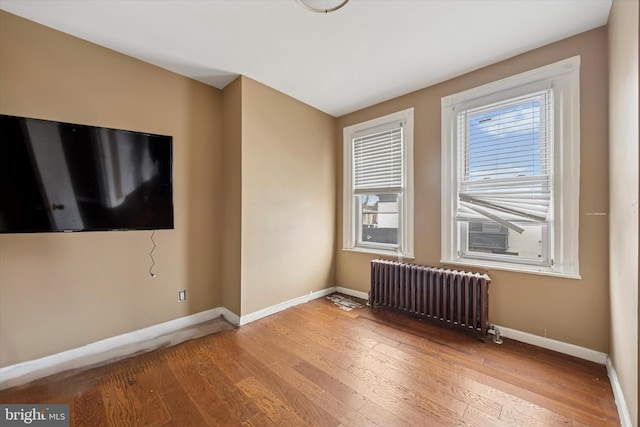 unfurnished room with baseboards, radiator heating unit, and hardwood / wood-style flooring