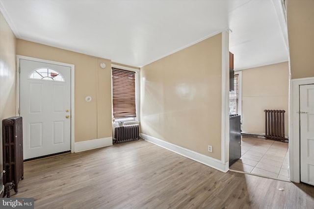 foyer entrance with light wood-style floors, radiator heating unit, and baseboards