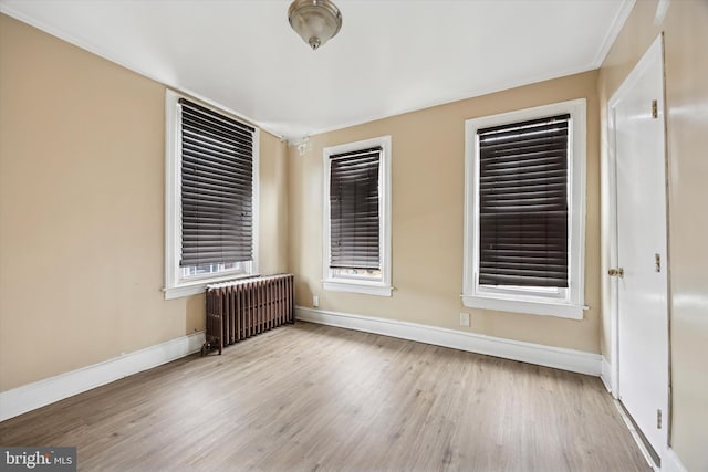 empty room with radiator heating unit, baseboards, and wood finished floors