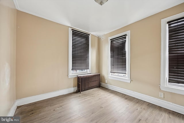 empty room featuring radiator, baseboards, and wood finished floors