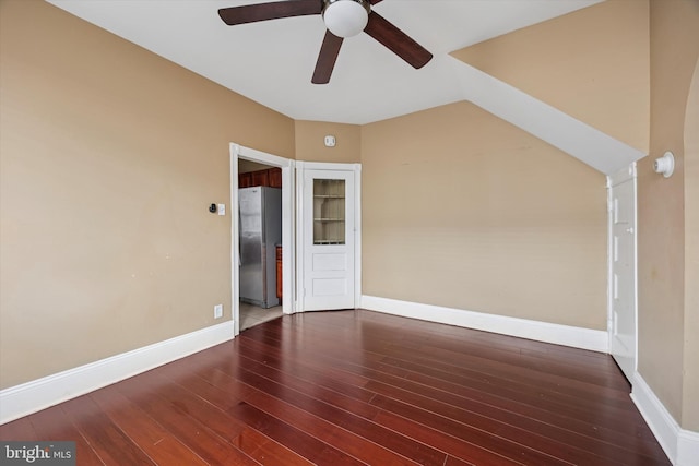 empty room with ceiling fan, vaulted ceiling, wood finished floors, and baseboards