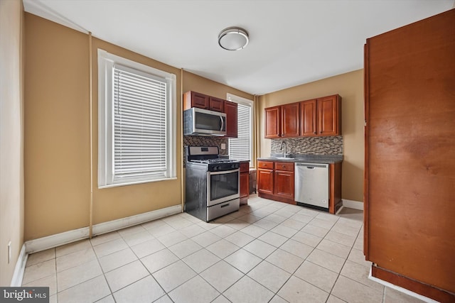 kitchen featuring light tile patterned floors, appliances with stainless steel finishes, a sink, and tasteful backsplash