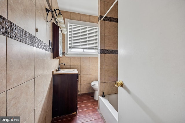 bathroom featuring toilet, vanity, tile walls, and wood finish floors