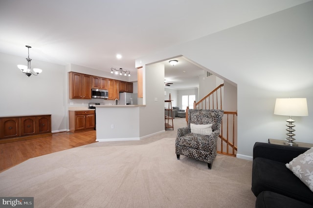 living room with light hardwood / wood-style floors and ceiling fan with notable chandelier