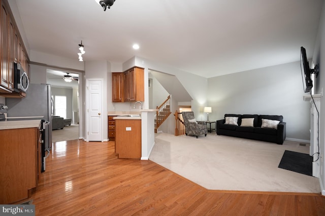 kitchen with sink, light hardwood / wood-style flooring, kitchen peninsula, a breakfast bar, and appliances with stainless steel finishes