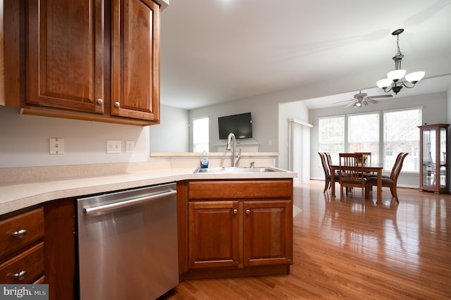 kitchen featuring sink, light hardwood / wood-style flooring, stainless steel dishwasher, pendant lighting, and ceiling fan with notable chandelier