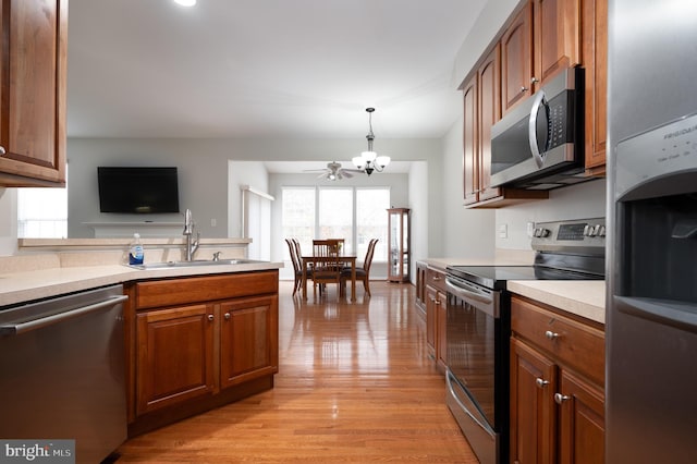 kitchen with ceiling fan with notable chandelier, hanging light fixtures, sink, light wood-type flooring, and appliances with stainless steel finishes