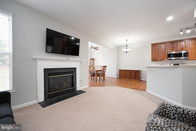 carpeted living room with ceiling fan with notable chandelier and plenty of natural light