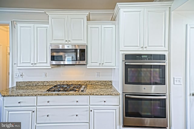 kitchen featuring appliances with stainless steel finishes, dark stone counters, and white cabinets