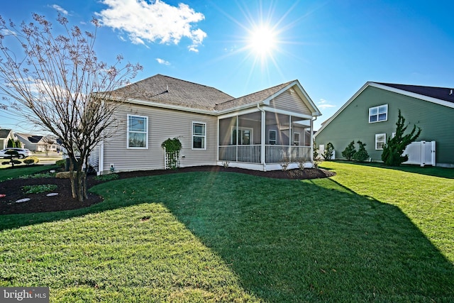 rear view of property with a lawn and a sunroom