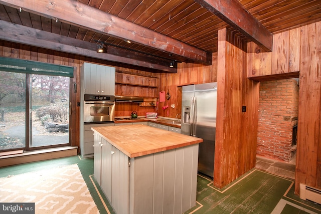 kitchen featuring beam ceiling, wood counters, a center island, and appliances with stainless steel finishes