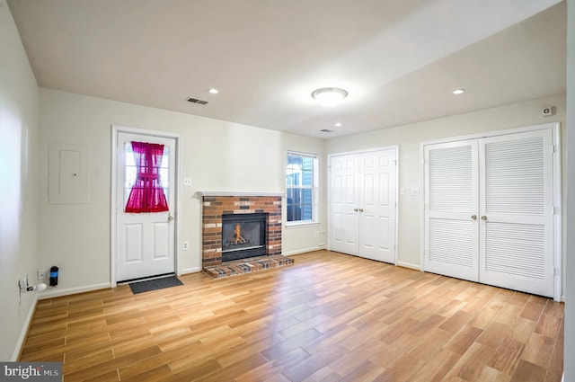 unfurnished living room featuring a fireplace, electric panel, and light hardwood / wood-style flooring