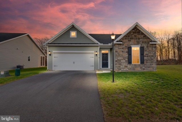 view of front of house with central AC unit, a garage, and a yard