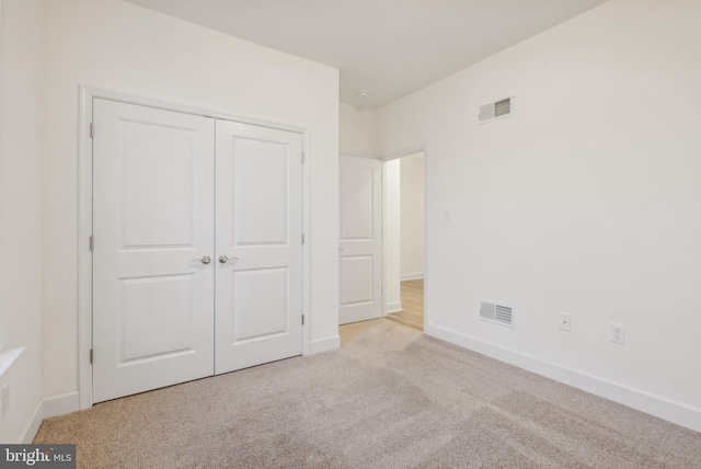 unfurnished bedroom with light carpet and a closet