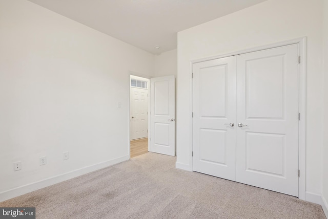 unfurnished bedroom featuring light colored carpet and a closet