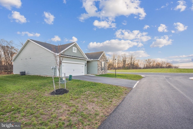 view of front of home with central AC, a front lawn, and a garage