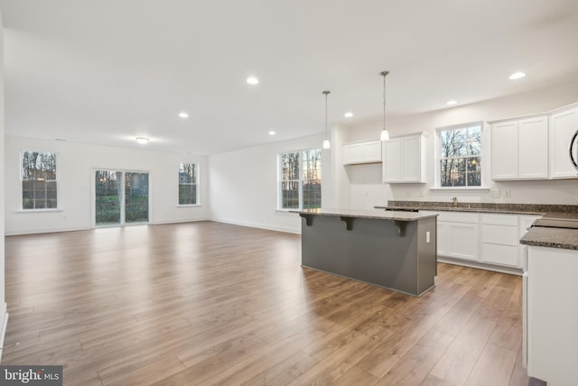 kitchen featuring white cabinets, light wood-type flooring, decorative light fixtures, and a kitchen island