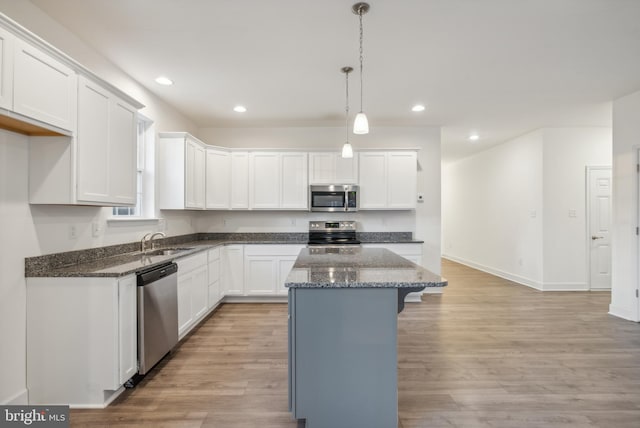 kitchen with white cabinetry, sink, hanging light fixtures, light hardwood / wood-style flooring, and appliances with stainless steel finishes