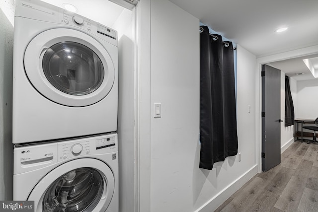 laundry area featuring stacked washer / drying machine and light wood-type flooring