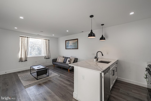 kitchen with sink, dark hardwood / wood-style flooring, stainless steel dishwasher, kitchen peninsula, and pendant lighting