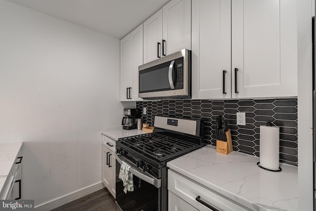 kitchen with light stone countertops, white cabinets, stainless steel appliances, and dark hardwood / wood-style floors