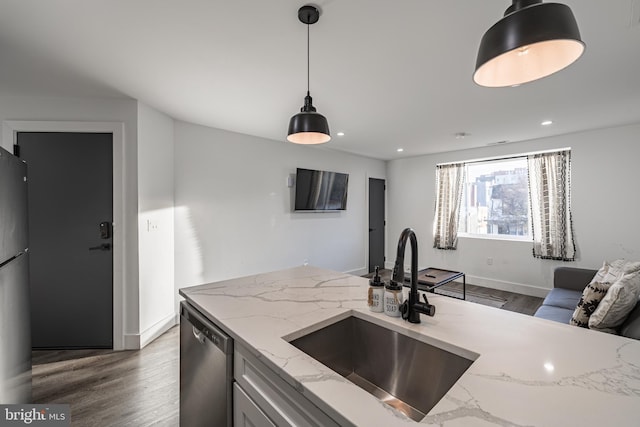 kitchen featuring appliances with stainless steel finishes, light stone counters, dark wood-type flooring, sink, and decorative light fixtures