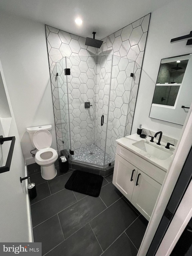 bathroom featuring toilet, vanity, tile patterned floors, and an enclosed shower