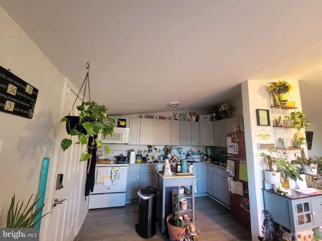 kitchen featuring gray cabinetry, lofted ceiling, dark wood-type flooring, and white appliances