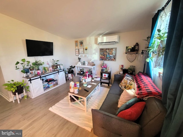 living room with wood-type flooring, vaulted ceiling, a wall mounted AC, and a healthy amount of sunlight