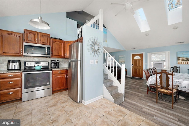 kitchen featuring ceiling fan, high vaulted ceiling, decorative backsplash, appliances with stainless steel finishes, and light wood-type flooring