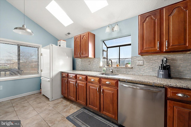 kitchen with a skylight, stainless steel dishwasher, sink, pendant lighting, and white fridge