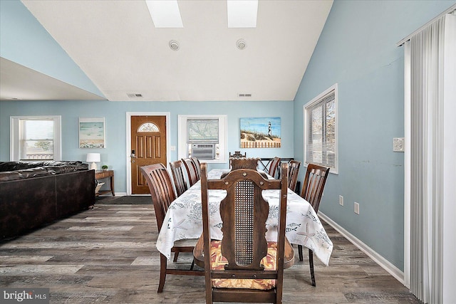 dining area featuring vaulted ceiling with skylight, cooling unit, and dark hardwood / wood-style flooring