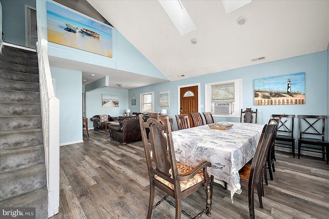 dining area featuring hardwood / wood-style floors, cooling unit, high vaulted ceiling, and a skylight