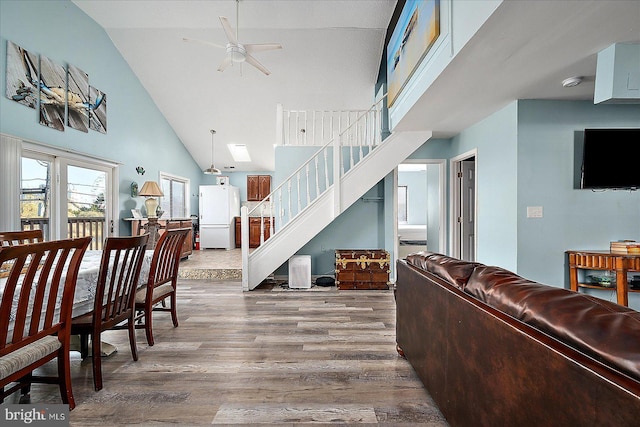 living room with hardwood / wood-style floors, high vaulted ceiling, and ceiling fan