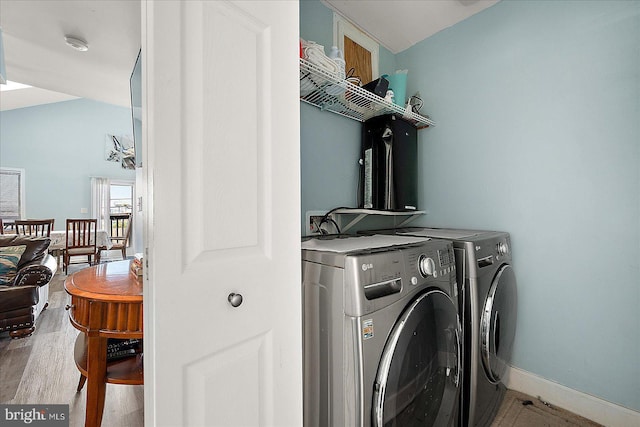 clothes washing area featuring independent washer and dryer and light hardwood / wood-style flooring