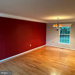 unfurnished room featuring wood-type flooring and an inviting chandelier