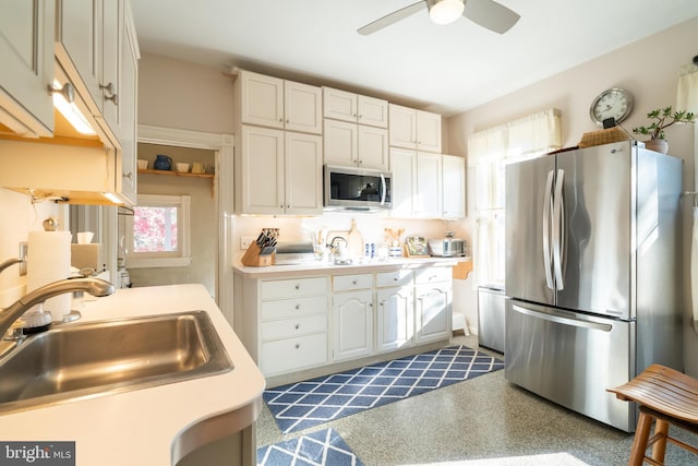 kitchen with appliances with stainless steel finishes, white cabinetry, ceiling fan, and sink