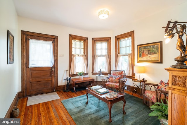 sitting room with dark wood-type flooring and a healthy amount of sunlight