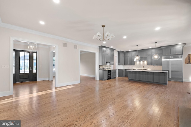 unfurnished living room with a chandelier, crown molding, light hardwood / wood-style floors, and sink