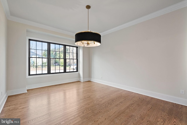 spare room featuring wood-type flooring, ornamental molding, and a chandelier