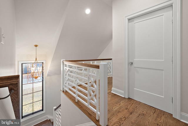 stairway featuring wood-type flooring and an inviting chandelier