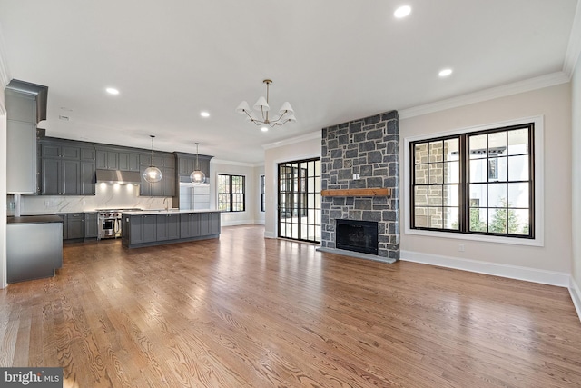 unfurnished living room with a fireplace, hardwood / wood-style floors, an inviting chandelier, and ornamental molding