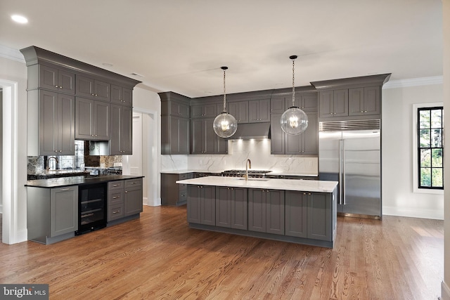 kitchen with pendant lighting, stainless steel built in fridge, gray cabinets, wood-type flooring, and beverage cooler