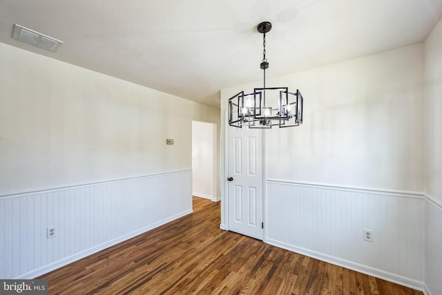 unfurnished dining area with dark hardwood / wood-style flooring and an inviting chandelier