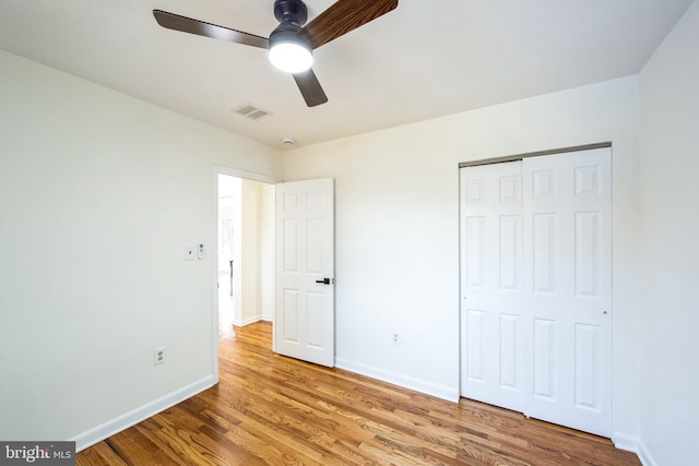 unfurnished bedroom with ceiling fan, light wood-type flooring, and a closet