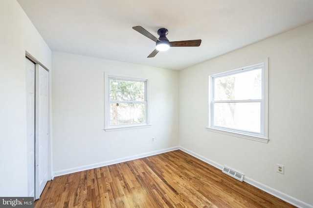 unfurnished bedroom with hardwood / wood-style flooring, ceiling fan, a closet, and multiple windows