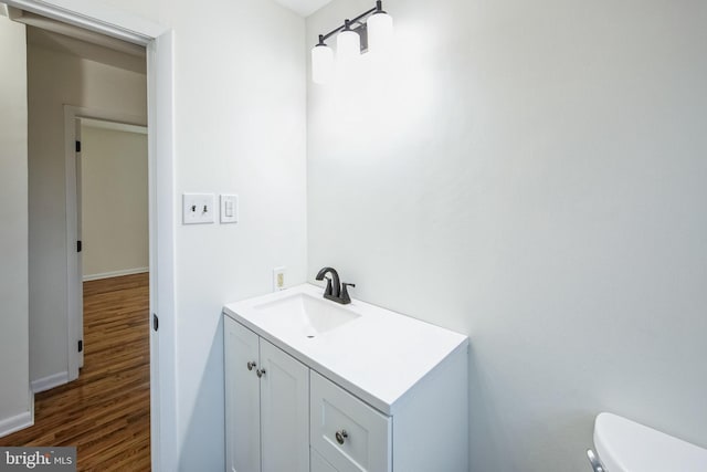 bathroom featuring toilet, vanity, and hardwood / wood-style flooring